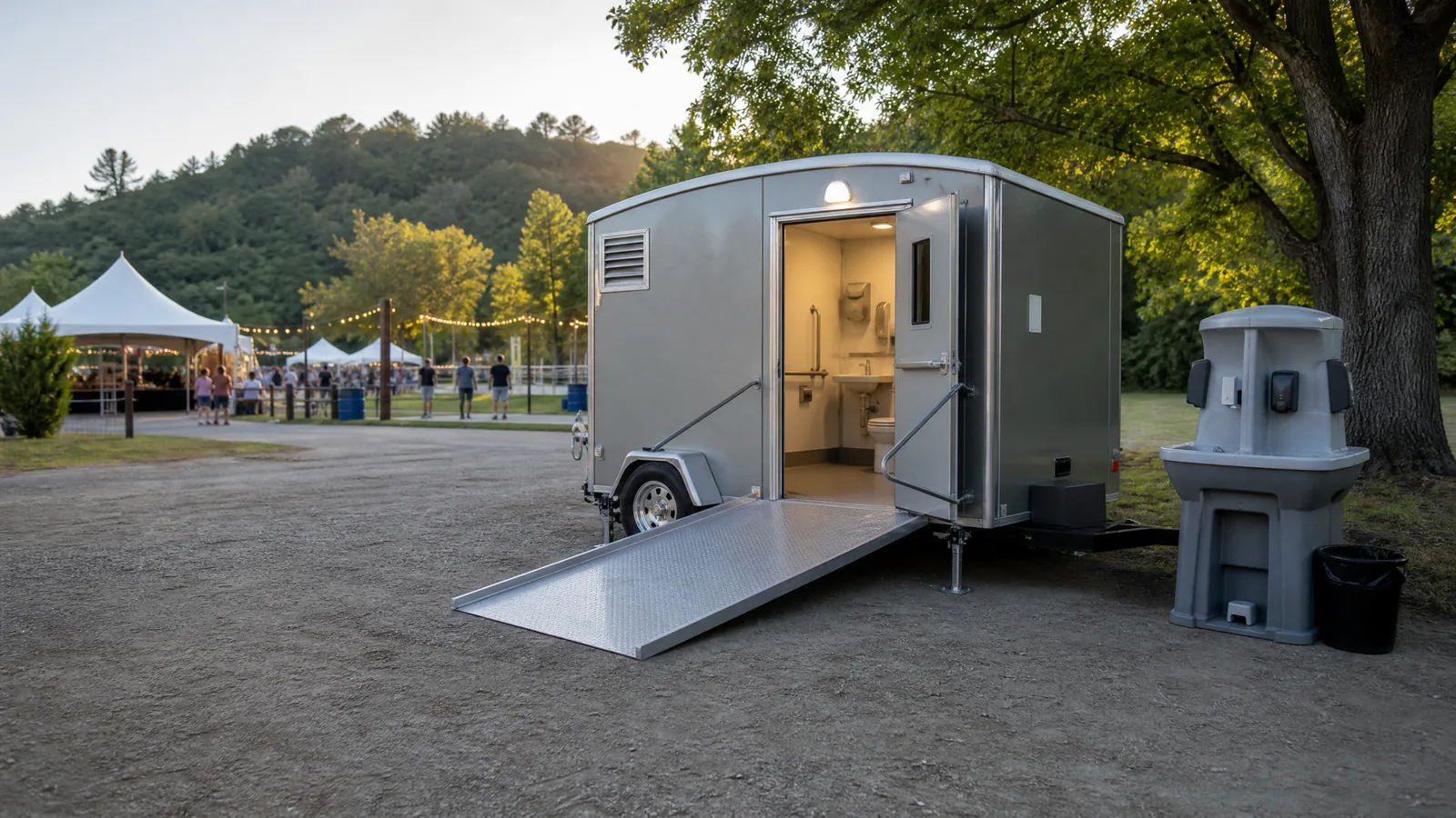 Level firm path leading from an event lawn toward an accessible portable restroom